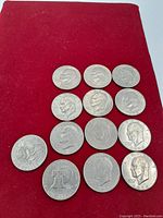 Top view of 12 Eisenhower dollar coins arranged on a red cloth, showing obverse sides with Eisenhower's profile.