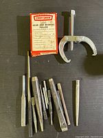 Photo of Craftsman gear and bearing puller in original box alongside assorted punches and drifts on a black surface.