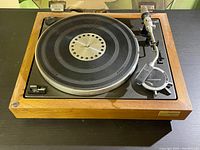 Clear image of Sony 5520 turntable showing wood frame, black platter with holes, and tonearm with automatic mechanism.