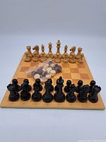 Full view of the chess board with all chess pieces arranged on it and the bag of checkers pieces placed on the board.