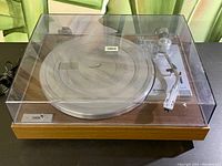 Yamaha YP-211 record player with wooden base and clear dust cover, showing overall unit from a top-front angle.