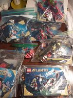 Five LEGO Atlantis sets displayed mostly disassembled in ziplock bags with manuals on a surface.