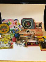 Full front view of all toys in the assortment, showcasing crochet set, clock, dolls, boxed model plane, croquet set, and small toys