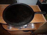 Top-down view of large black cast iron skillet showing smooth flat surface and handle.