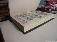 Opened hardcover stock book showing thick pages filled with stamps.