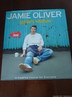 Front cover photo of 'Jamie Oliver Jamie's Kitchen' cookbook showing Jamie Oliver in casual pose against a blue background.