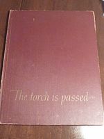 Large maroon hardcover book with gold embossed title 'The torch is passed...'.