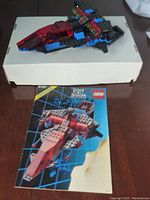 Photo of the Lego Police Jet model assembled, showing the red cockpit and instruction booklet underneath on a white box