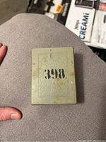 Closed pale green metal case with number '398' printed on top, showing surface wear and paint chips.