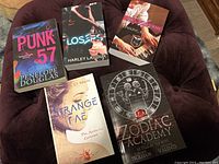 Six paperback indie author books arranged on a cushioned surface to show front covers.
