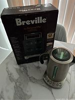 Boxed Breville Personal Pie maker and Breville tea maker placed on marble surface