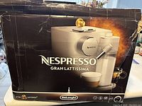 Cardboard packaging box showing Nespresso Gran Lattissima branding and DeLonghi logo