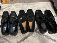 Three pairs of men's dress shoes: Steve Madden double monk straps, Perry Ellis loafers, Aldo lace-ups, all black, arranged on carpet.