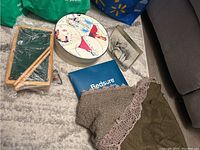 Overview showing miniature pool table, boxed Bedsure pillowcase, small glass art, dessert plates, and brown shawl on floor and couch