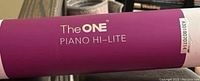 Photo showing the product branding 'The ONE Piano Hi-Lite' on a purple and white cylindrical packaging/or strip.