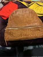 Tan brown backpack with eyelet details shown on top, zipper closure visible