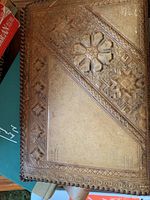 Close-up of a hand-tooled leather book cover with intricate embossed designs.