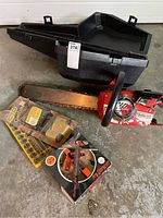 Full lot including the red Home Lite chainsaw, black carrying case, unopened sharpening tool, and Oregon cord cutter kit laid out on the floor.