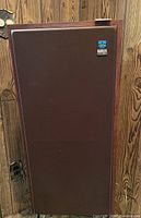 Full front view of KossFire Model 210 speaker against wood-paneled background.