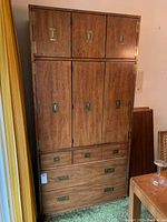 Full front view of the closed wooden bar cabinet showing multiple drawers and cupboard doors with brass handles