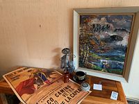 View of painting, figurine, poster, and pottery items arranged on a wooden surface.