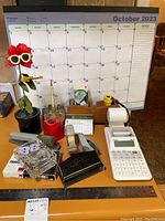 Full view of office supplies and decorative items including the calendar, calculator, flower decoration, and baskets on a desk.