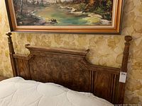 Close-up of the queen size bed's wooden headboard with turned posts and white mattress visible.
