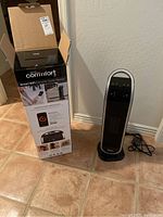 One Atomi Smart WiFi Ceramic Tower Heater outside of the box with control panel and cable visible, next to unopened heater box.