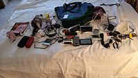 Wide view of all items laid out on bed including electronics, cables, small tools and totes