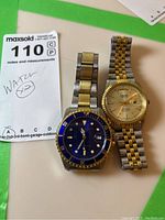 Two men's wristwatches placed side-by-side, showing front dial, metal two-tone bracelets and general condition.