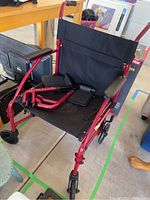 Red folding Walgreens brand wheelchair with black fabric seat and backrest, footrests folded and attached, manual brakes visible.