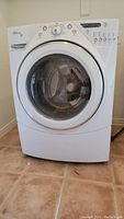 Front view of white Whirlpool front load washer with control panel and door visible.