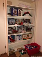 Shelves with various Christmas decor items including pillows, figurines, sleigh, centerpiece basket, and boxed light sets.
