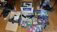 Opened Apex Digital box, Alpine unit and Intellivision box on floor with scattered game cartridges and DVD movie cases