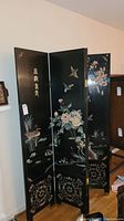 Full view of the four-panel black folding screen with birds, flowers, and Asian characters painted on it