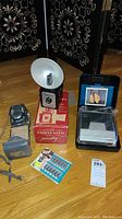 Full view of all cameras and accessories in the lot including Yashica 44 camera, Imperial Six-Twenty flash camera in box, Polaroid Spectra System camera in packaging, and flash bulbs pack