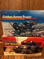 Photo showing original boxes of Golden Arrow Buggy and Malibu Off Roader radio controlled cars stacked, labeled Radio Shack, both boxes show wear and tears