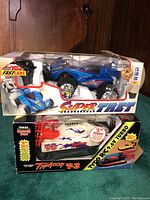 Photo showing two boxed RC cars, FastLane Super Tret off-road car on top and Tyco Typhoon T-3 RC boat below.