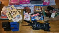 Top view of assortment including Batman Batmobile toy, Boggle game box, Crayola game, Pooh books, coin banks and other paper items.