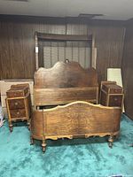 Full view of vintage wooden bedframe with attached nightstands and footboard, showing curved headboard and footboard with carved detail and turned legs.