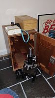 Full view of microscope, wooden carrying case with open door, Surgipath micro slide carrier box, and other micro slides on floor
