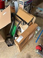Photo of several boxed and unboxed items including a picnic grill box, bird feeder parts, and other yard items in a pile on floor