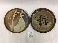 Photo of two pottery side plates with abstract designs and earthy colors, showing top views of each plate side by side.