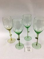 Four light green hand blown wine goblets with distinctive twisted knot detail on the stems shown together.