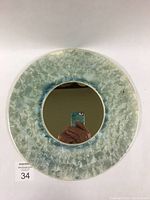 Full top-down photo of the round mirror with crystalline glaze ceramic frame, showing green and blue flower-like crystal patterns.
