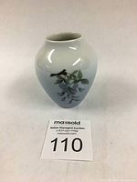 Front angle view displaying the overall shape, size, and color of the vase including the light blue gradient background and floral design.