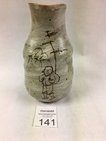 Front view of the Japanese hakeme glazed vase showing the man walking among trees and birds painted in black over white slip glaze.