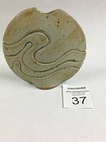 Front view of the round ceramic bud vase with carved wave pattern and oatmeal glaze, showing overall form and texture.