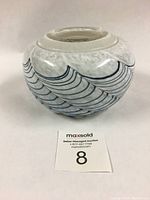 Front and side view of Robert Held art glass vase showing curved blue line pattern on white mottled glass.