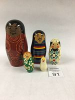 Full set of five Russian nesting dolls arranged from largest to smallest, showing unique hand-painted designs and doll sizes.